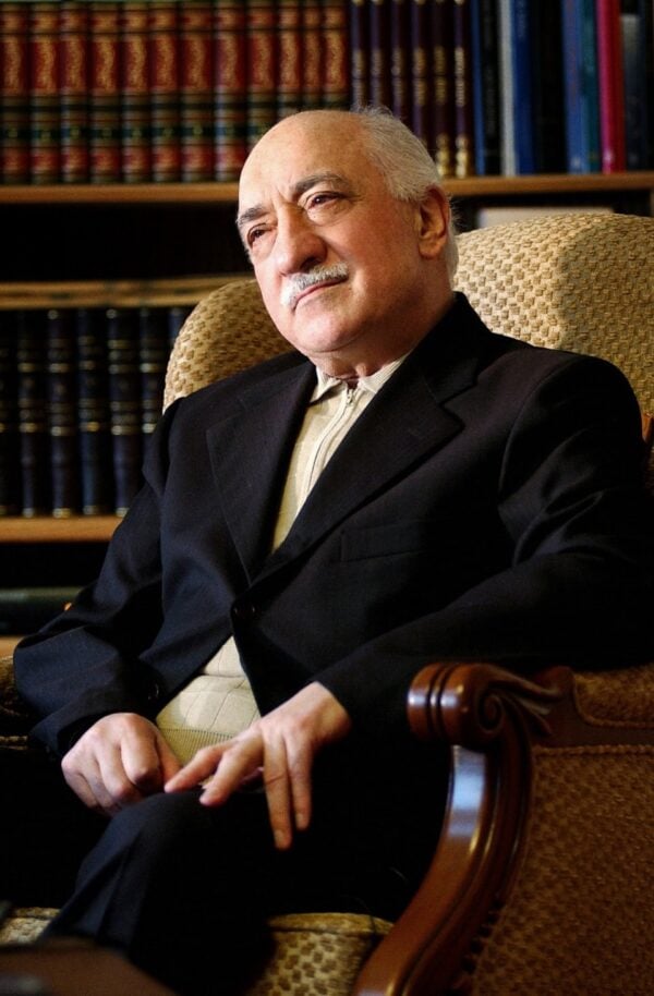 M. Fethullah Gülen așezat într-un fotoliu, în fața unei biblioteci cu cărți